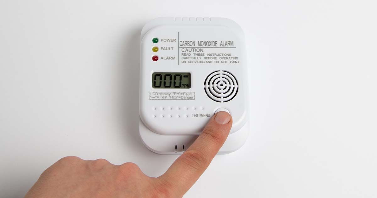 Person pressing button on carbon monoxide detector.