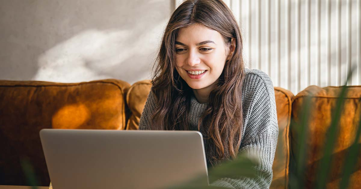 Woman in living room looking at laptop.