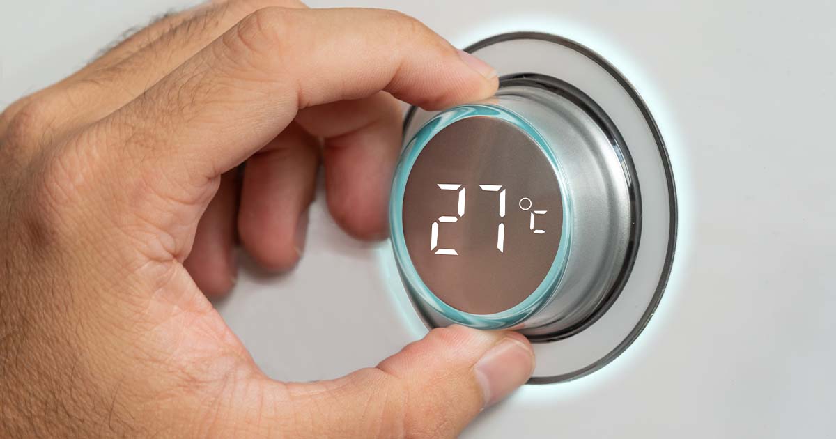 Man turning up smart thermostat.