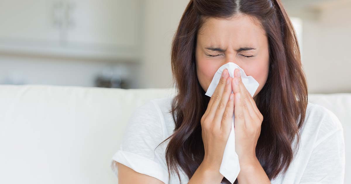 Woman blowing nose into tissue.