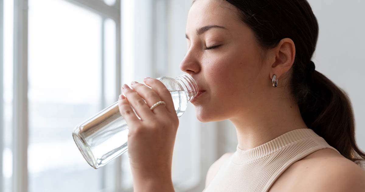 Woman drinking water in a bottle at home