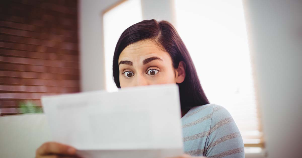 Woman with bulging eyes while looking at piece of paper.